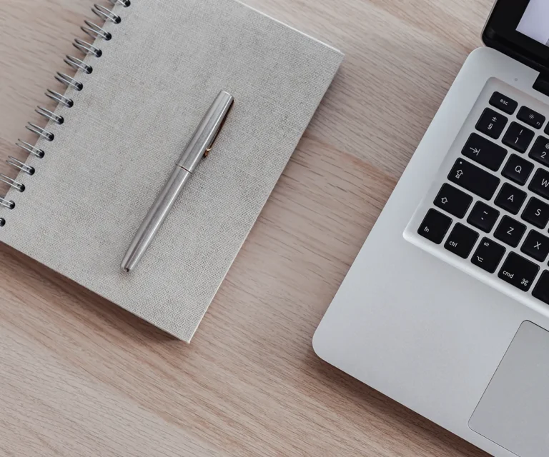 Laptop und Notizbuch auf einem Schreibtisch – Symbol für die Optimale Website Struktur von Coaching-Angeboten auf einer Website.