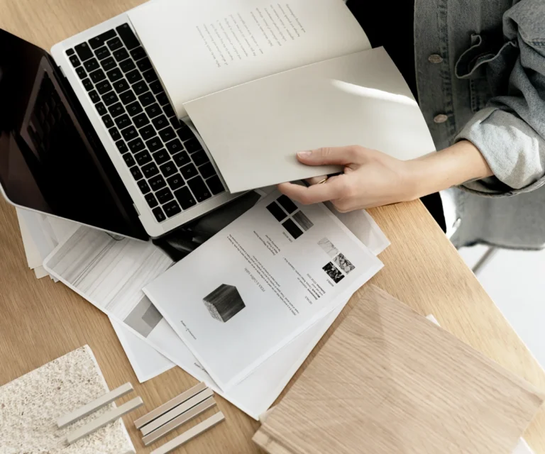 Ein aufgeräumter Arbeitsplatz mit Laptop und Design-Entwürfen, der die Planung einer professionellen Website symbolisiert.