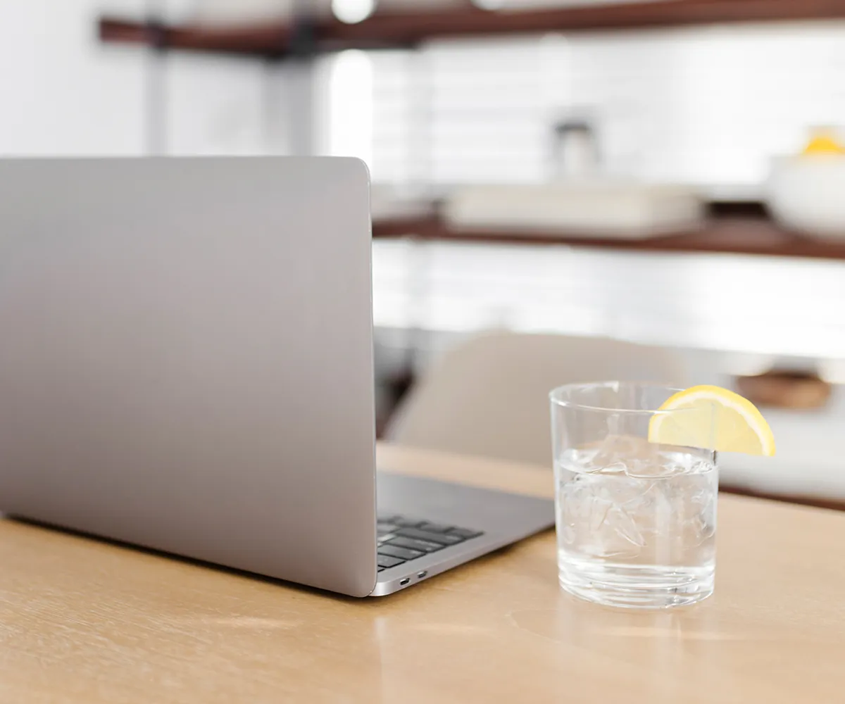 Minimalistischer Arbeitsplatz mit Laptop und Getränk, Symbol für eine Website, die nicht konvertiert