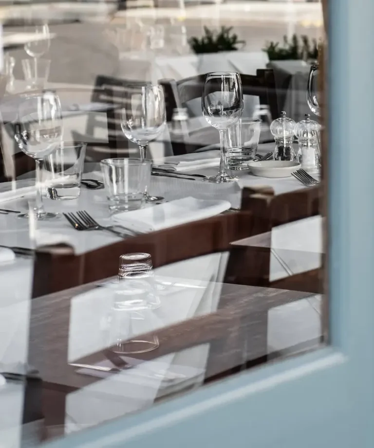 Vorbereitetes Restaurant mit gedeckten Tischen hinter einer Fensterscheibe als Symbol für eine Website ohne Besucher