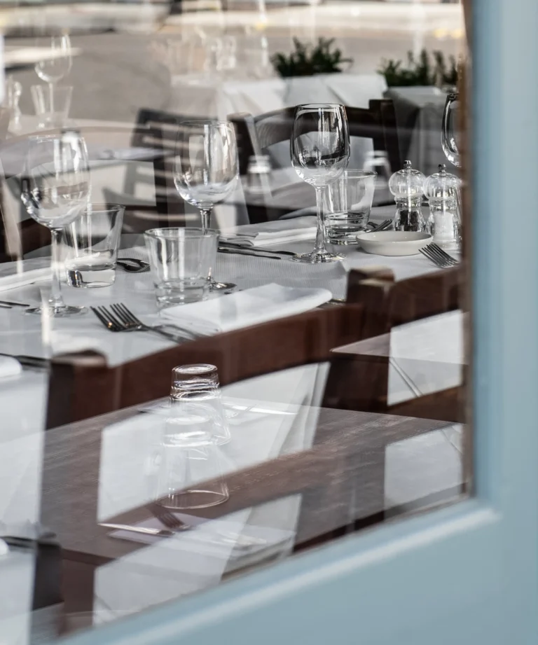 Vorbereitetes Restaurant mit gedeckten Tischen hinter einer Fensterscheibe als Symbol für eine Website ohne Besucher
